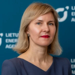 Agnė Bagočiūtė, V&scaron;Į Lietuvos energetikos agentūros direktorė, konferencijos prane&scaron;ėja. Portretinė nuotrauka &ndash; moteris su &scaron;viesiais, tiesiais plaukais, dėvinti tamsų &scaron;varką. Ji žiūri tiesiai į kamerą, neutrali veido i&scaron;rai&scaron;ka. Fonas &ndash; tamsus, su logotipu.