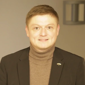 Martinas Nyderis, Lietuvos Respublikos aplinkos ministerijos Būsto prieinamumo politikos grupės vyresnysis patarėjas, konferencijos prane&scaron;ėjas. Portretinė nuotrauka &ndash; vyras su trumpais plaukais, dėvintis &scaron;varką ir auk&scaron;ta apykakle megztinį. Jis &scaron;ypsosi. Fonas &ndash; &scaron;viesus.